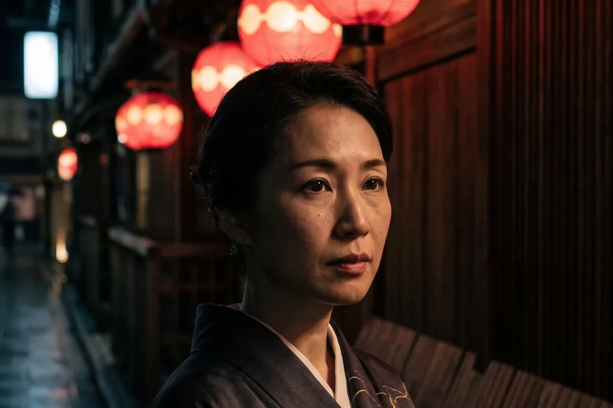 Close-up portrait of a Japanese woman in a dark kimono under red paper lanterns at night